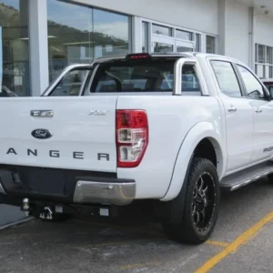 Rear view of a white Ford Ranger XLT pickup truck with black alloy wheels parked outside a dealership.