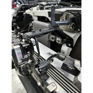 Close-up of performance intercooler installation with mounting brackets and wiring harness visible.