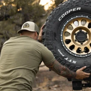 Person mounting Method Race Wheels 315 Gold Black Lip with Cooper Discoverer STT Pro tire on off-road vehicle