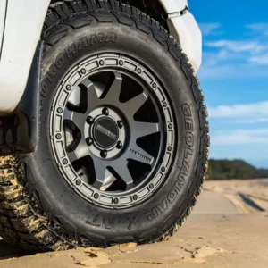 Method Race Wheels 317 Matte Titanium – Side Angle Method Race Wheels 317 matte titanium installed on 4x4 vehicle driving on sandy beach