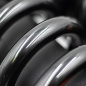Close-up of a black automotive coil spring with glossy finish.
